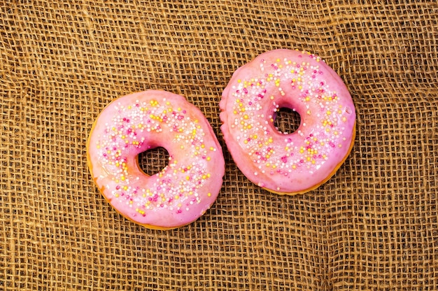 Twee zoete donuts met roze glazuur en sprinkles.