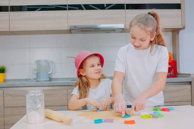 Twee zusjes bloggers bereiden koekjes in de keuken.