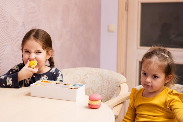 Twee zussen eten heerlijke smakelijke zoete kleur macarons