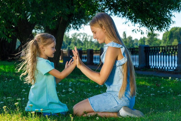 Twee zussen in jurken spelen samen in het park op het gras