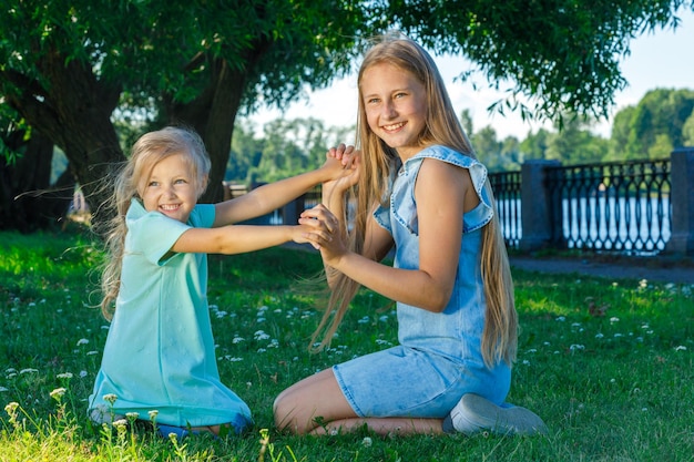 Twee zussen in jurken spelen samen in het park op het gras