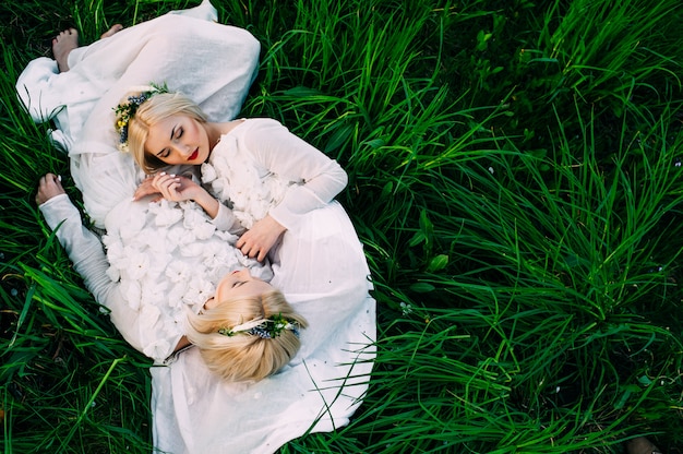 twee zussen tweeling liggend op groen gras