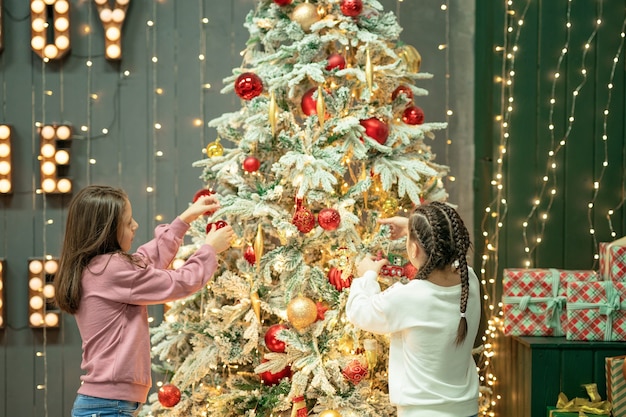 twee zussen versieren een kerstboom prettige kerstdagen en gelukkig nieuwjaar concept