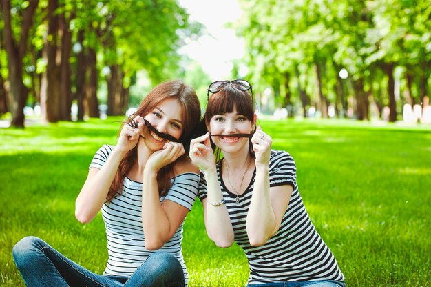 Twee zussen, vrienden hebben plezier, lachen, eten suikerspin, lopen in een zomergroen pretpark. Gelukkig
