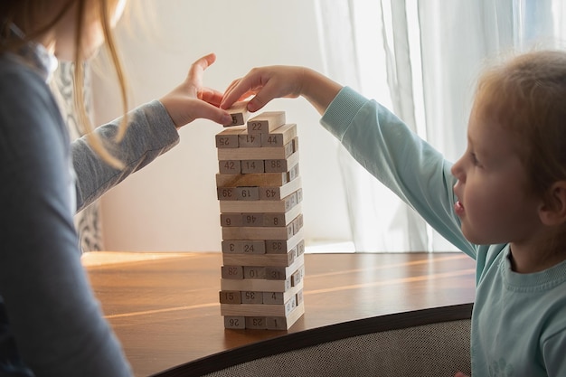 Twee zustermeisjes zijn bezig met een bordspel en leggen houten stokjes neer