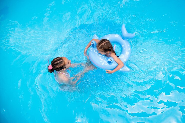 Twee zustermeisjes zwemmen in een zwembad met blauw water en hebben een fan Zomer Familievakantie