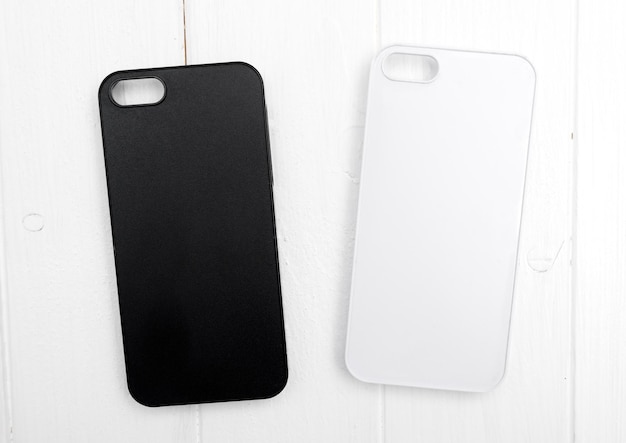 Foto twee zwart-witte iphone cases op wit hout klassiek iphone design topview