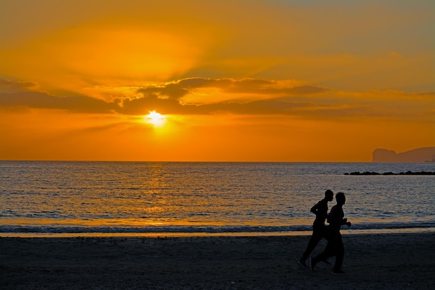 Twee zwarte mannen rennen op de kust bij zonsondergang