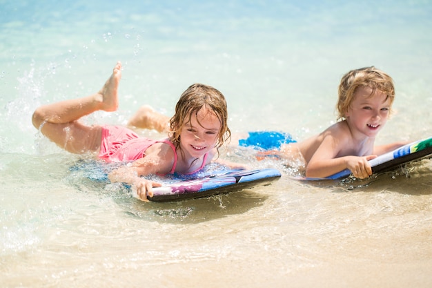 Tweelingbroer en -zus om plezier te hebben met surfen in de oceaan