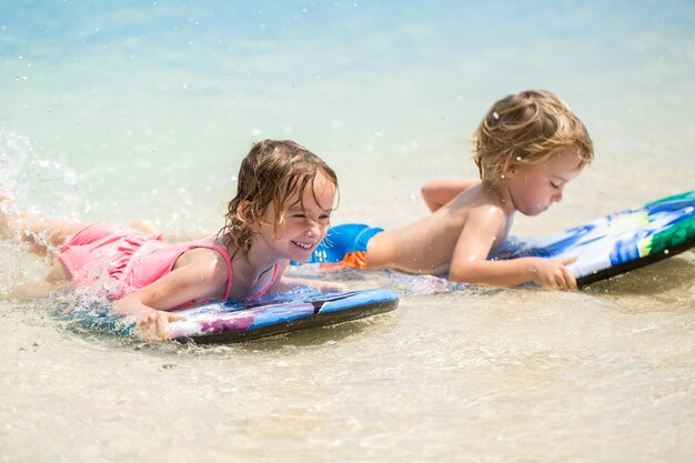 Tweelingbroer en zus om plezier te hebben met surfen in de oceaan