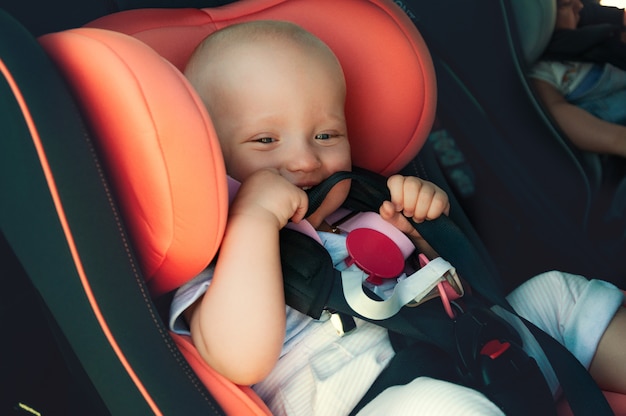 Tweelingenjongen en meisje in kinderzitjes in de auto. Veiligheidsvervoer voor baby's. Kinderen tot een jaar.