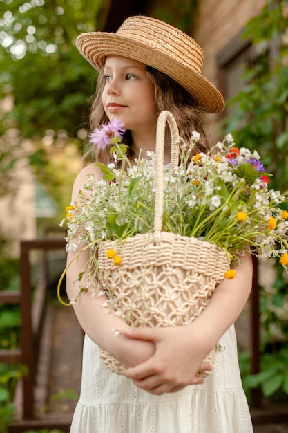 Tween meisje met mand met wilde bloemen genieten van zomervakantie in landhuis