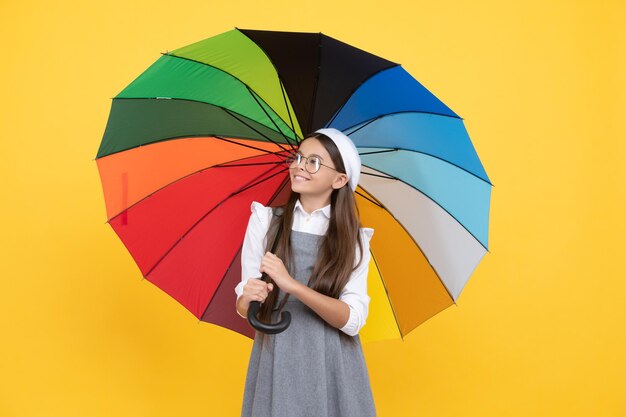 Tween met levendige regenbescherming gelukkig schoolmeisje in glazen vrolijk tienerkind onder kleurrijke parasol kind in baret met regenboogparaplu herfstseizoen regenachtige weersvoorspelling terug naar school