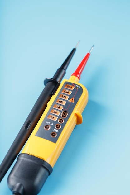 Tweepolige spanningsindicator close-up op een blauwe achtergrond. Testen en verifiëren van elektrische netwerken