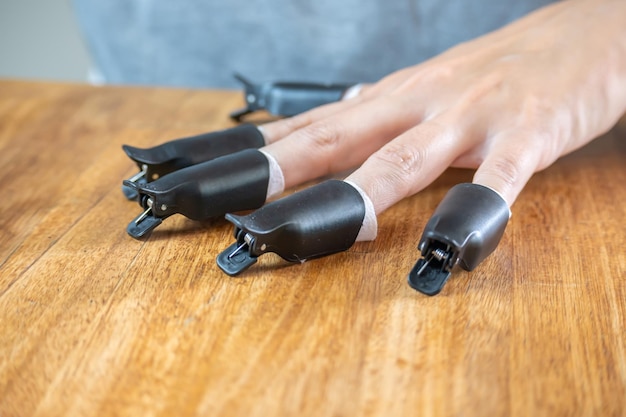 Photo tweezers for removing nail polish in the hands of a young woman