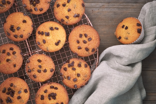 Twelve freshly baked choco chip muffins cooling off on wire mesh