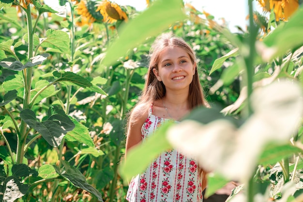 A twelve-year-old teenage girl walks in a field of sunflowers