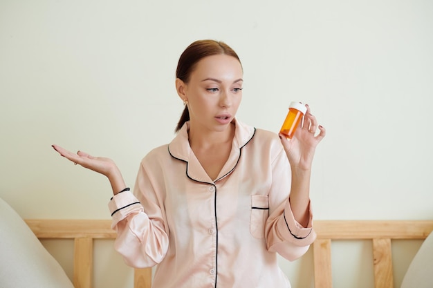 Twijfelende vrouw met pillencontainer