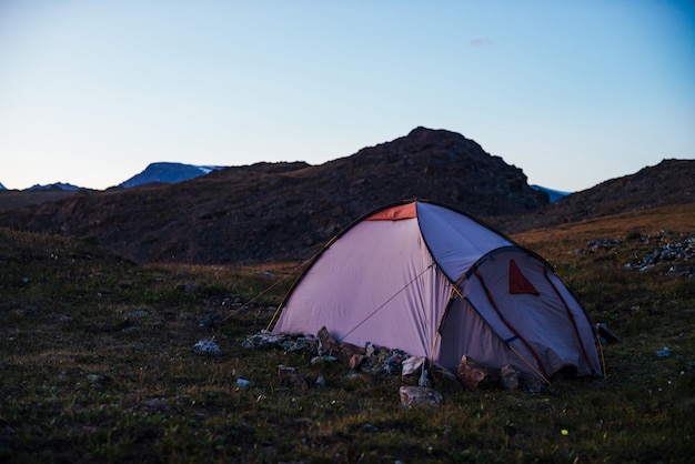 Twilight in mountains with tent on pass in violet light.