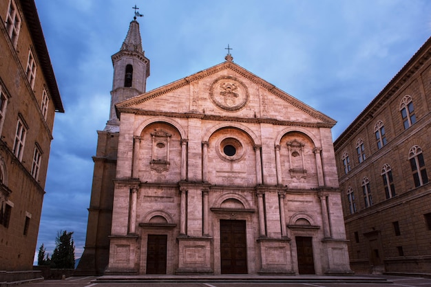 Twilight view of the Pienza Assumption of the Virgin Mary Cathedral with dark blue sky. Facade from white marble. Religious travel destinations background.