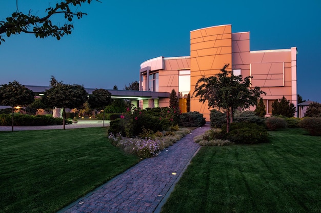 Twilight zicht op modern landhuis en verzorgde aangrenzende groene omgeving in de zomer