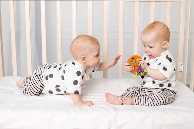 Twin babies play in the crib, early development of children up to a year