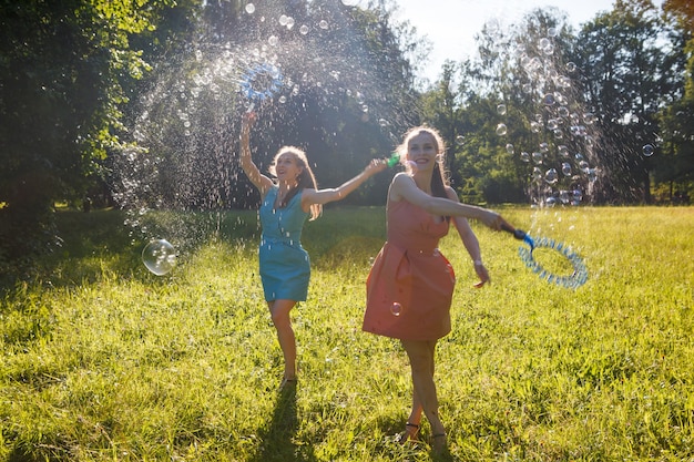 Twin girls make big soap bubbles in the park