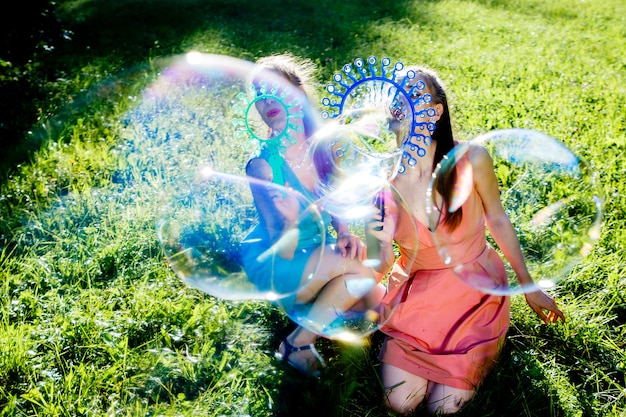 Twin girls make big soap bubbles in the park