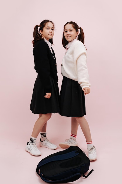 Twin schoolgirls with twin tails posing one in cardigan other in jacket