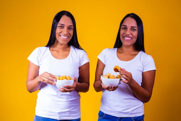 Twin sisters eating mini fried snacks