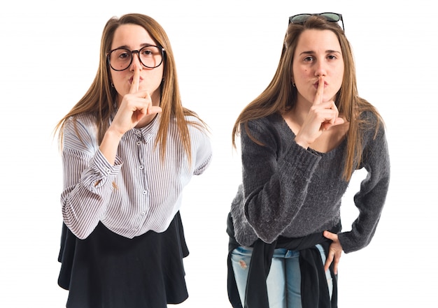 Twin sisters making silence gesture 