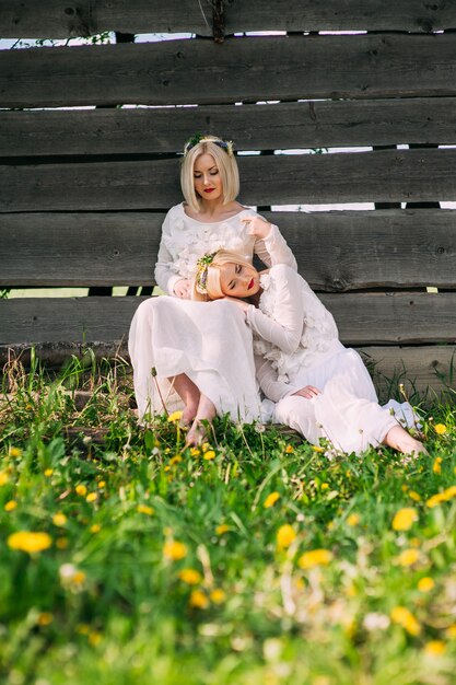 Twin sisters sitting at a wooden wall