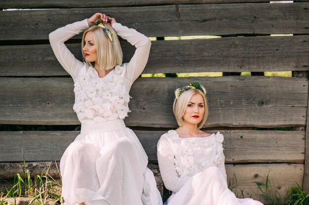 Twin sisters sitting at a wooden wall