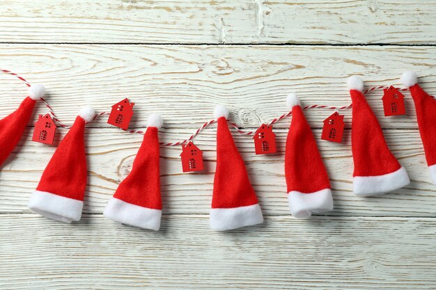 Twine with red houses and santa hats on white wooden background