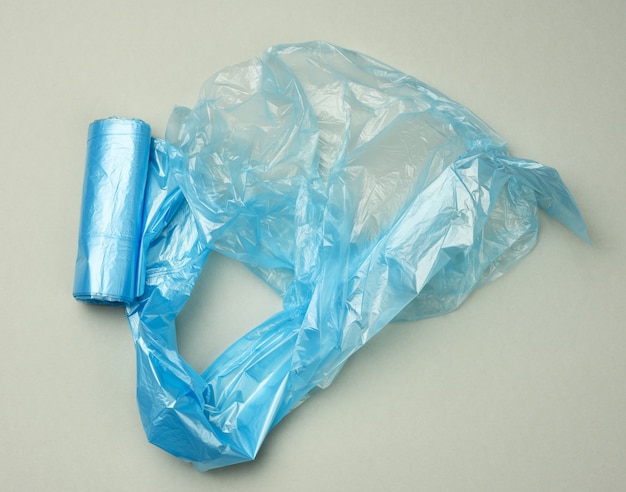 Photo twisted blue plastic bags for bin on a gray background, top view