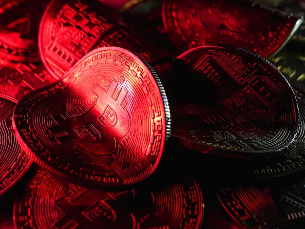 Twisted coins with bitcoin symbol on red light. Concept of a cryptocurrency market crisis.