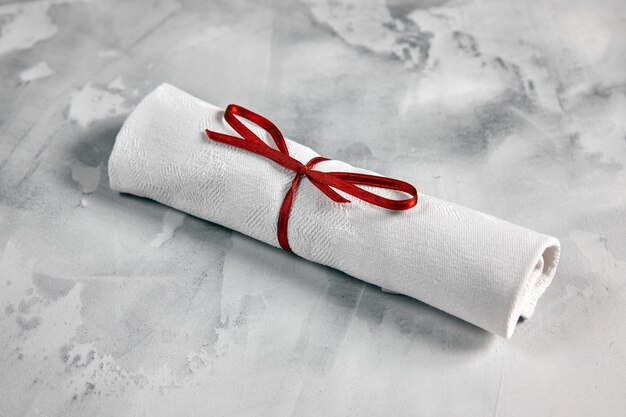 twisted napkin tied with red bow, lies on white marble