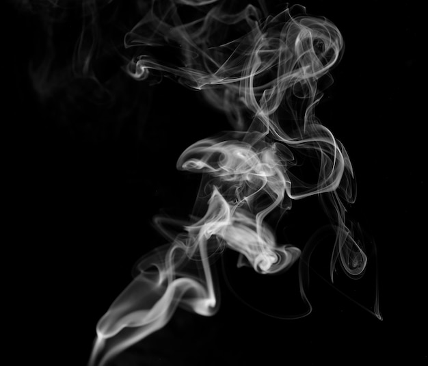 Pennacchi attorcigliati di fumo fumo movimento su sfondo nero linee di fumo astratte