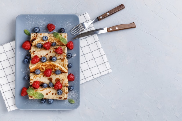 Twisted thin pancakes with raspberries and blueberries decorated with mint