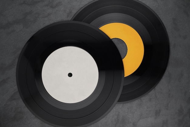 Two 7-inch single vinyl records on black slate background. Top view