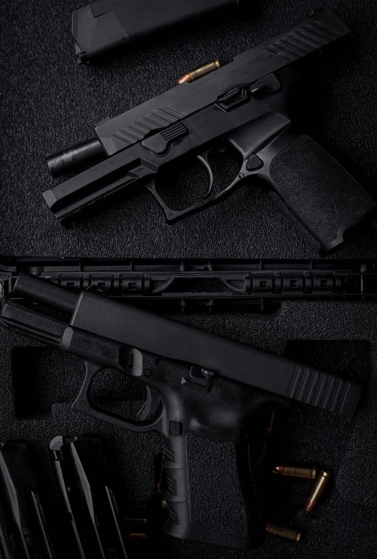 Photo two 9mm pistols hold slides on a wooden table