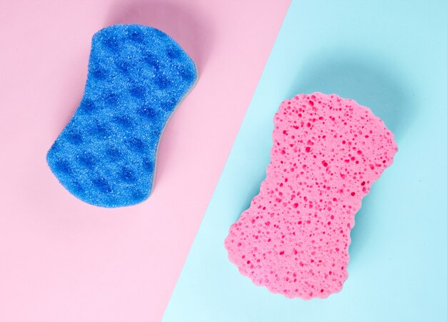 Two abrasive double-sided sponges on a pink-blue pastel background