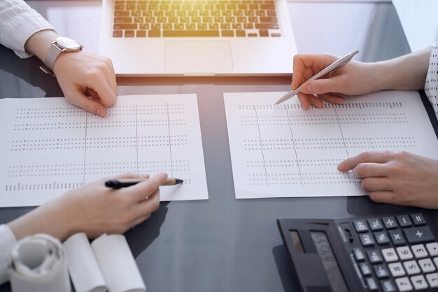 Photo two accountants use a calculator and laptop computer for counting taxes or revenue balance business audit and taxes concepts