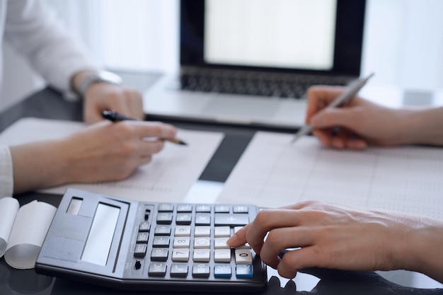 Two accountants use a calculator and laptop computer for counting taxes or revenue balance Business audit and taxes concepts