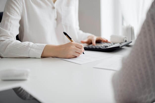 Two accountants using a laptop computer and calculator for counting taxes at white desk in office Teamwork in business audit and finance