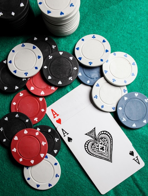 Due assi sul tavolo da gioco verde. due carte da gioco e fiches da poker su un tavolo da casinò verde.