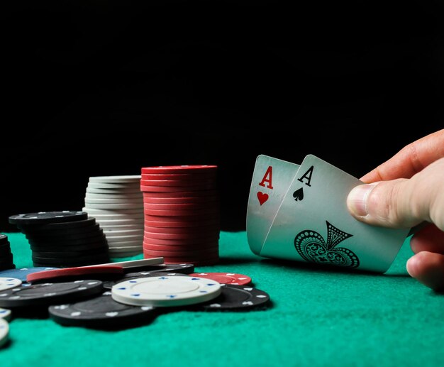 Photo two aces in the hands of a close-up. two playing cards and poker chips on the green casino table