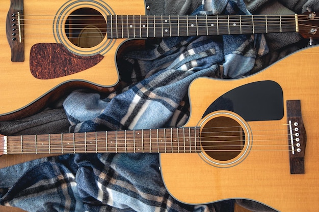 Two acoustic guitars on a cozy plaid top view