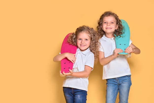 Two Active and happy girls with curly hair having fun with penny board,