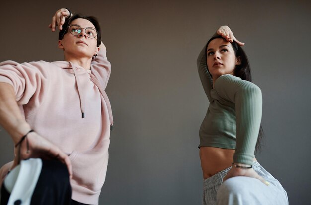 Two active teenagers keeping their arms over heads while training in studio